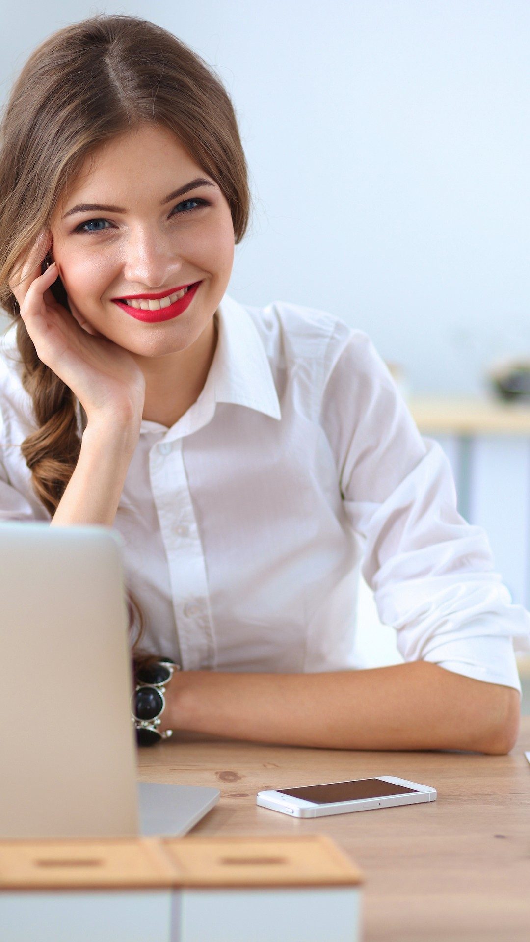 Attractive businesswoman sitting on desk in the office